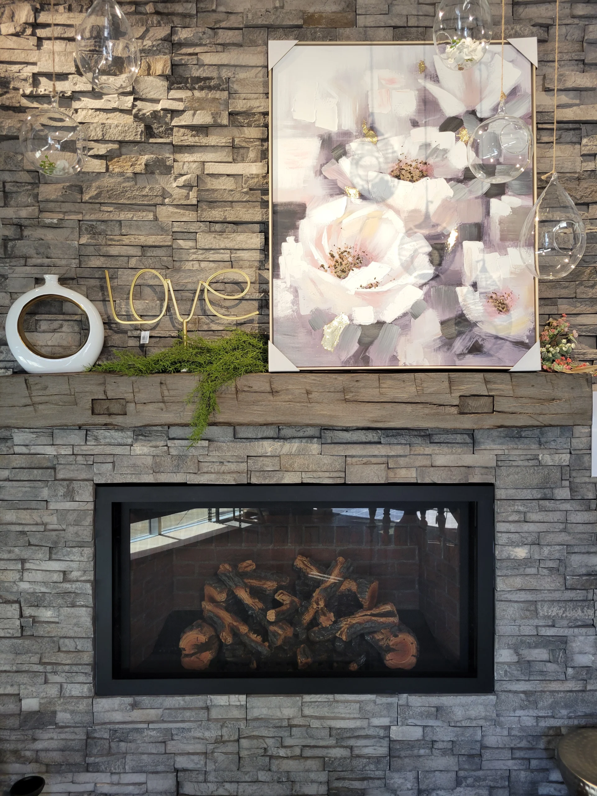 framed wall art of soft pink flowers with home decorations on a gray brick mantle